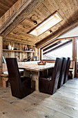 Dark leather chairs around dining table with corner bench in modern wooden house