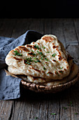 Plate with delicious naan bread and cloth napkin placed on weathered lumber table