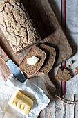 From above loaf of tasty ryecorn bread placed on cloth napkin near spoon of grain on wooden background