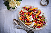 Peach, figs, grapes, cherry tomatoes, mozzarella and walnuts salad on a serving plate