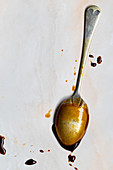 Thick golden syrup dripping off a large spoon.