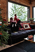 Girls on black sofa next to window in festively decorated living room of chalet