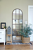Arched, lattice mirror on wall and eucalyptus planted in basket in living room