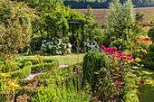 Blick auf Garten mit Hortensien und Tor zum Laubengang
