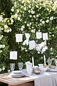 Table set in white and beige in garden in front of viburnum bush
