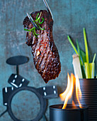 Flank steak cooking over an open flame