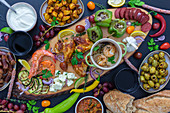 Antipasti plate with various vegetables, shrimps, dips, fruit, bread and chicken