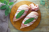 Raw chicken breast with bacon and sage