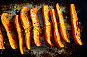 Oven-roasted pumpkin wedges on a baking tray