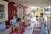 Set table on festively decorated terrace outside Falu-red wooden house