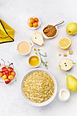 Zutaten für gesundes Frühstück: Haferflocken, Birnen und gelben Kirschen mit Honig