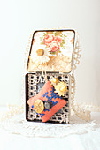 Old tin decorated with wallpaper, everlasting flowers, lace, pin cushion and buttons