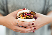 Hands of woman holding traditional Asian sandwich steamed bun with meat and vegetables