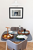 Black-and-white striped chairs at small table below picture on wall