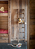 Ladder leaning against rustic wooden wall made from reclaimed wood next to bunk beds