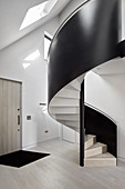 Black, modern spiral staircase in foyer of architect-designed house