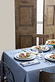 Gedeckter Tisch mit pastellblauer Tischdecke und gefüllten Vorspeisentellern