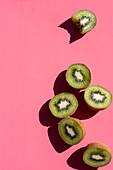 Kiwi halves, one with a bite taken out, on a pink surface