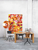 Various chairs around wooden table in front of abstract painting