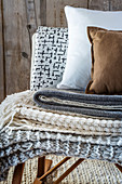 Stack of knitted blankets and cushions in natural shades