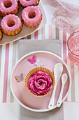 Pink ranunculus in muffin case on plate as table decoration