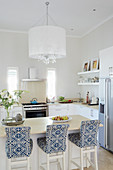Bar stools with blue-and-white loose covers at breakfast bar in elegant, open-plan kitchen