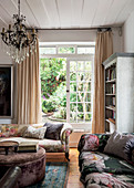 Crystal chandelier above sofas with vintage-style floral print and velvet ottoman