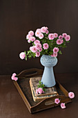 Rosa Asternstrauß in Vase auf antikem Holztablett