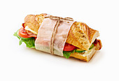 Fresh big baguette sandwich with bacon, chedder cheese, mustard, lettuce and vegetables