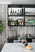 Home bar; bottles of spirits and glasses on mirrored shelves