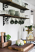 Vintage-style crockery on wooden shelves on wrought iron brackets