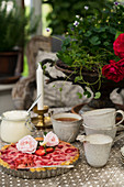 Erdbeer-Kuchen und graues Geschirr auf romantisch gedecktem Tisch