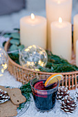 Mulled wine and spiced biscuits next to tray of candles and illuminated spheres