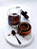 Kakaopulver in Glas, Holzschale und Sieb