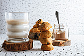 Tasty brown cookies on wooden coasters standing on sackcloth and glass of dairy beverage