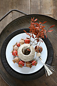 Painted poppy seed heads and ball of twine used as vase for leafy twig