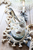 Collection of buttons and antique spoons in jar surrounded by tasselled trim