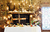 Festlich gedeckter Tisch in historischem Gemäuer dekoriert mit Kreuz und Kerzen