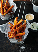 Sweet potato fries in a frying basket next to two dips