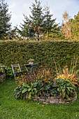 Stauden im Beet mit Natursteinmauer im spätsommerlichen Garten