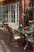 Rattanstühle am Gartentisch auf der Terrasse am Backsteinhaus