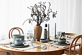 Table set simply in natural shades and decorated with branches and Easter eggs