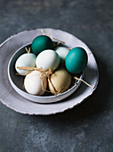 Various coloured eggs with straw in a ceramic bowl