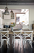 Dining table and chairs in front of open doorway leading into kitchen