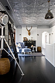 Studio lamp and ladder in open-plan interior with silver stucco ceiling