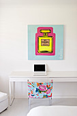 Poster above simple white desk and colourful chair