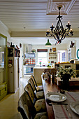 Dining table and chairs in open-plan interior with vintage-style kitchen in background