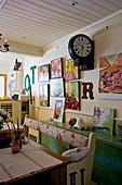 Sitzbank im Shabby Chic vor grünem Sideboard, Bahnhofsuhr und Bildergalerie an der Wand