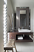 Modern washstand with countertop sink and rustic bench in bathrom