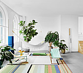 Liegestühle auf buntem Teppich, Zimmerpflanzen und Hängematte im Wohnzimmer